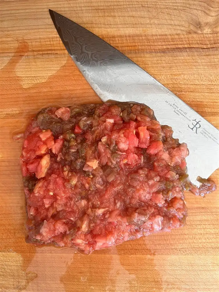 concasser les tomates au couteau sur une planche